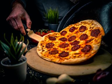 Szalámis pizza épp a deszkára helyezés közben